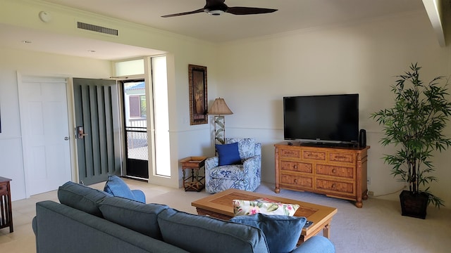 living room with ceiling fan, ornamental molding, and light carpet