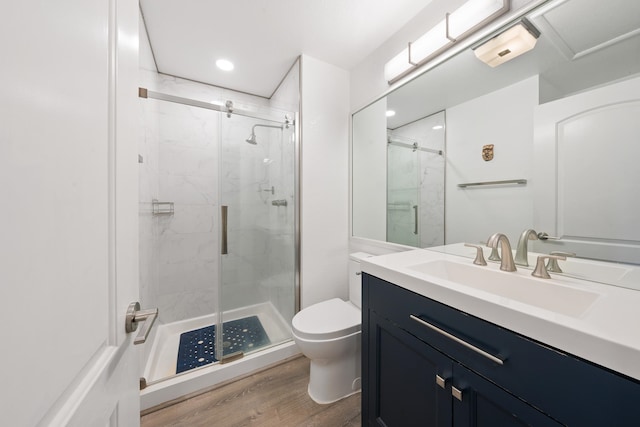 bathroom with vanity, toilet, a shower with door, and wood-type flooring