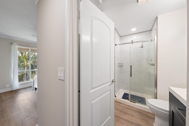 bathroom featuring a shower with shower door, vanity, hardwood / wood-style flooring, and toilet