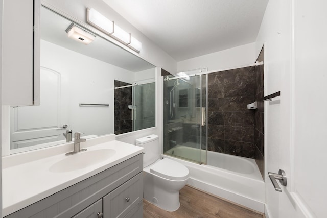 full bathroom featuring vanity, combined bath / shower with glass door, hardwood / wood-style flooring, and toilet