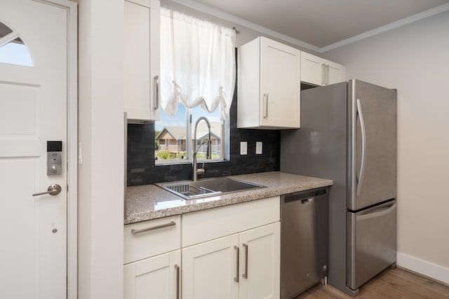 kitchen with a healthy amount of sunlight, tasteful backsplash, stainless steel appliances, and light hardwood / wood-style floors