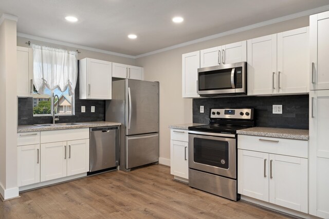 kitchen with light hardwood / wood-style floors, sink, backsplash, and stainless steel appliances