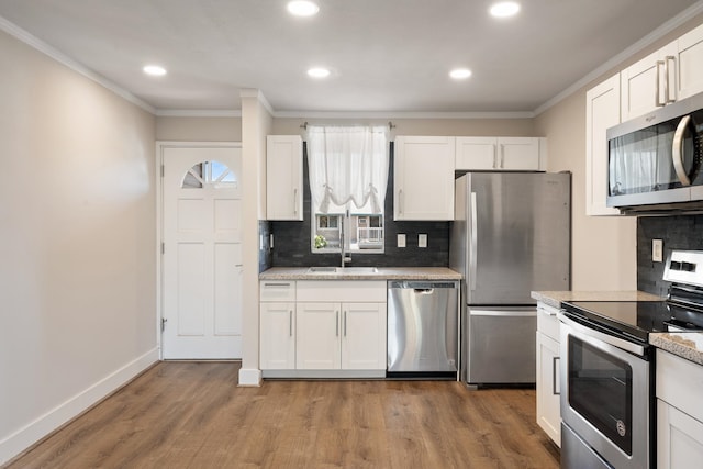 kitchen with white cabinets, hardwood / wood-style flooring, tasteful backsplash, and stainless steel appliances