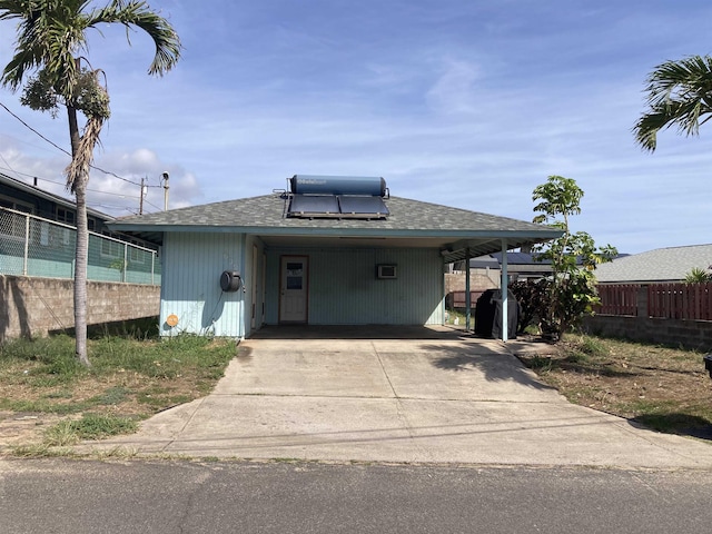 view of front of house with concrete driveway, roof with shingles, a carport, and fence