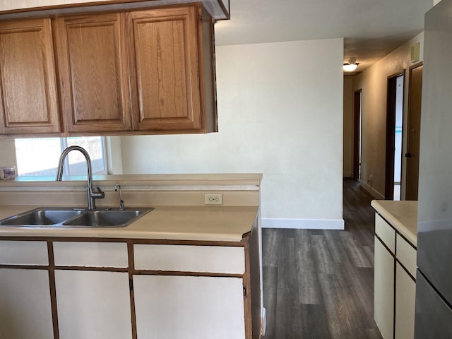 kitchen featuring dark wood-style flooring, light countertops, baseboards, and a sink