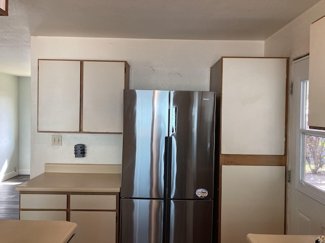 kitchen with white cabinetry, wood finished floors, light countertops, and freestanding refrigerator