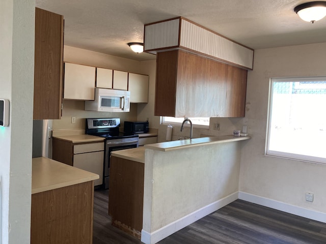 kitchen with white microwave, light countertops, stainless steel electric range, dark wood-style flooring, and a peninsula