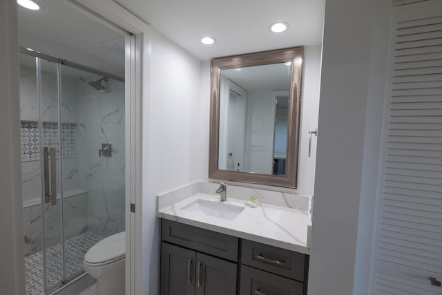 bathroom featuring vanity, a shower with door, and toilet