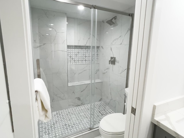 bathroom featuring toilet, a shower with shower door, and vanity