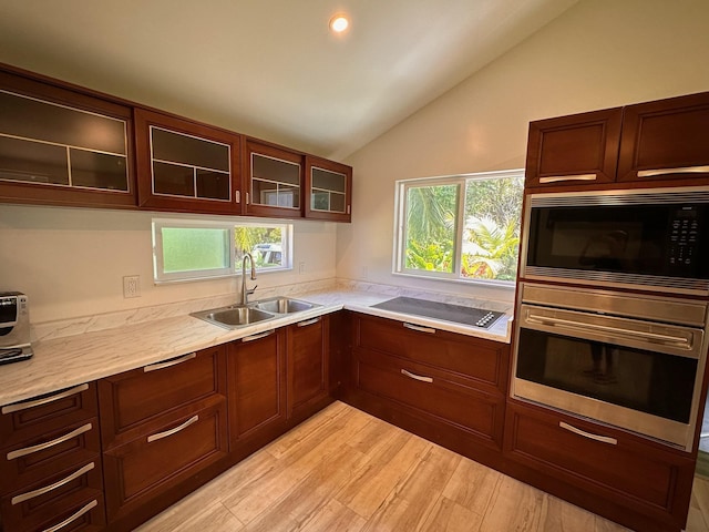 kitchen with black microwave, sink, stovetop, oven, and lofted ceiling