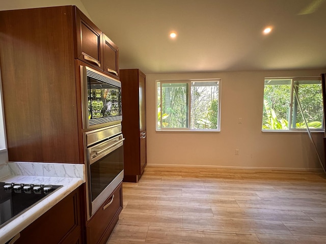 kitchen with black electric stovetop, light wood-type flooring, oven, and built in microwave