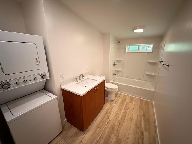 full bathroom featuring vanity, shower / washtub combination, hardwood / wood-style flooring, toilet, and stacked washer / dryer