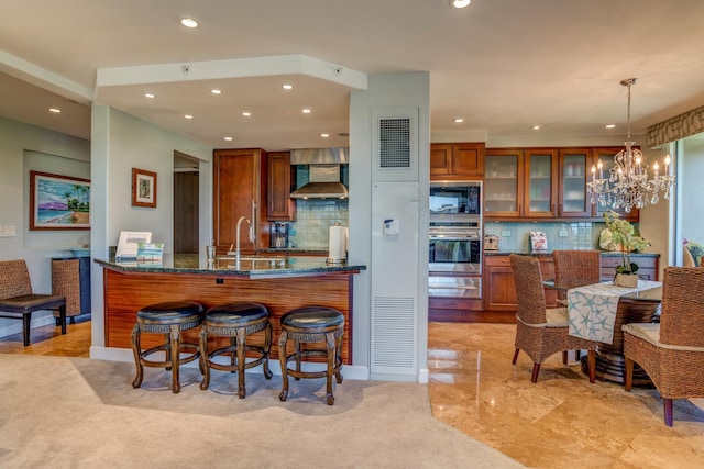 kitchen with sink, hanging light fixtures, black microwave, oven, and wall chimney exhaust hood