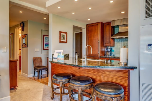 kitchen featuring sink, light carpet, dark stone countertops, kitchen peninsula, and decorative backsplash