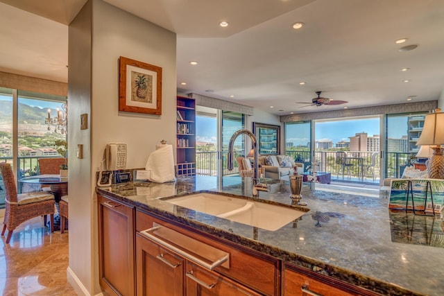 kitchen featuring ceiling fan, dark stone counters, and sink