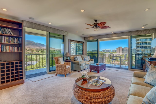 living room featuring light carpet, a mountain view, and ceiling fan