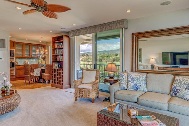 living room featuring light colored carpet and ceiling fan with notable chandelier