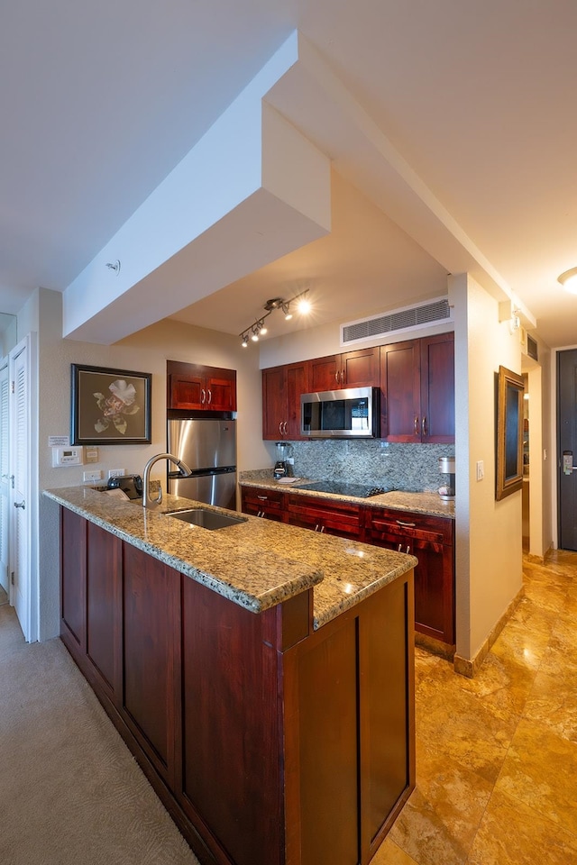 kitchen with light stone counters, sink, tasteful backsplash, rail lighting, and stainless steel appliances