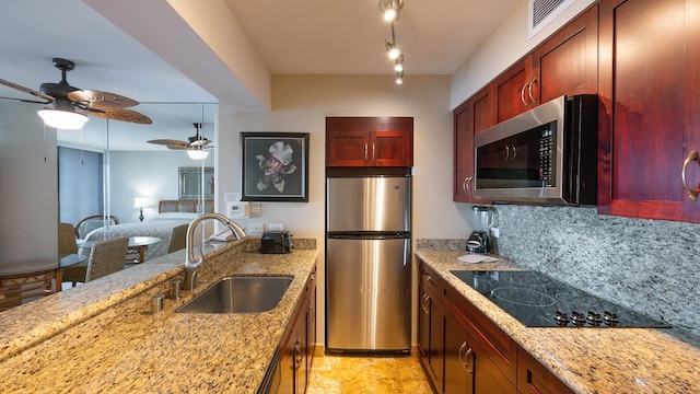 kitchen with appliances with stainless steel finishes, sink, ceiling fan, and light stone countertops