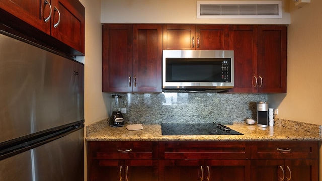 kitchen with backsplash, stainless steel appliances, and light stone countertops