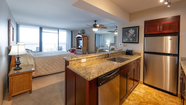 kitchen with appliances with stainless steel finishes, ceiling fan, sink, kitchen peninsula, and light stone countertops