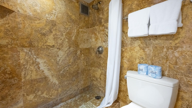 bathroom featuring toilet and a tile shower