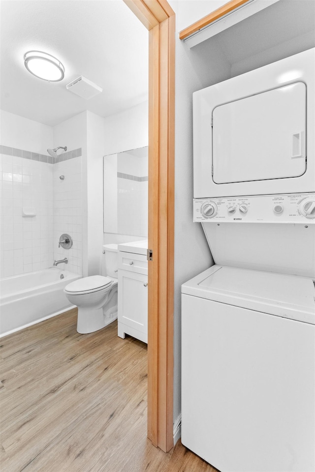 washroom with light hardwood / wood-style floors and stacked washing maching and dryer