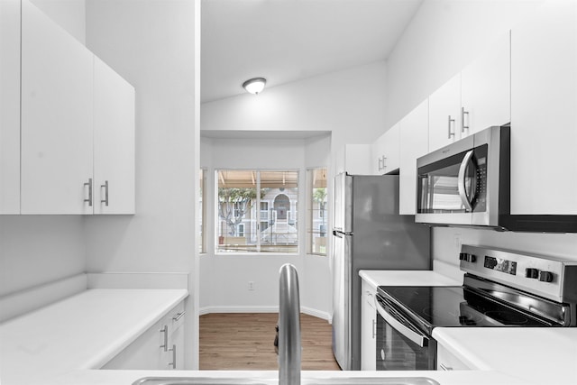 kitchen with sink, white cabinetry, vaulted ceiling, stainless steel appliances, and light hardwood / wood-style floors