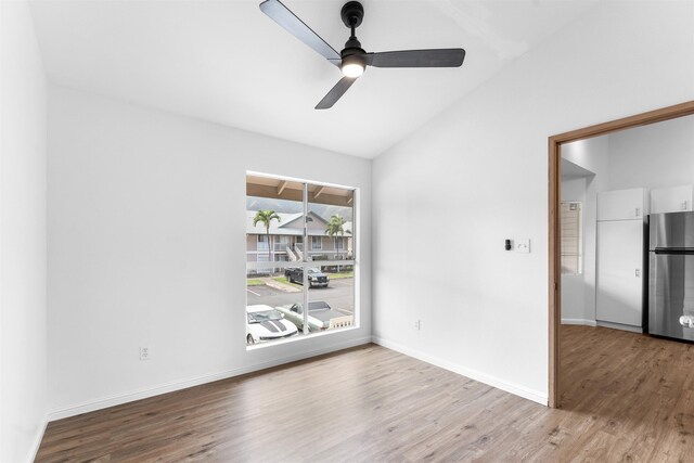 spare room with ceiling fan, vaulted ceiling, and light wood-type flooring