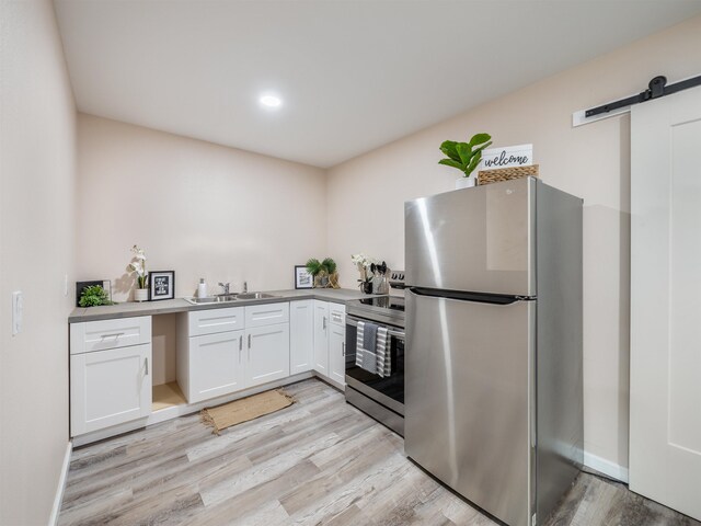 145 W Kane St, Kahului, HI 96732 - kitchen featuring a barn door, sink, light hardwood / wood-style flooring, appliances with stainless steel finishes, and white cabinets