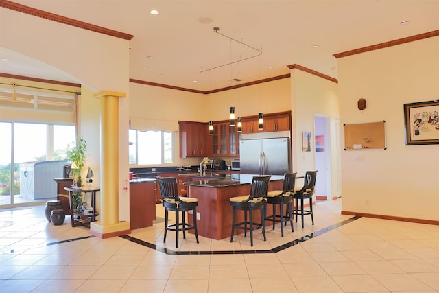 kitchen with pendant lighting, light tile patterned floors, a center island, stainless steel built in fridge, and ornate columns