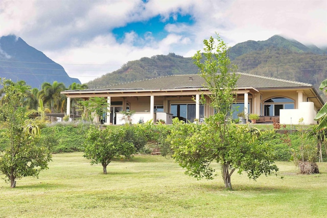 rear view of house with a yard and a mountain view