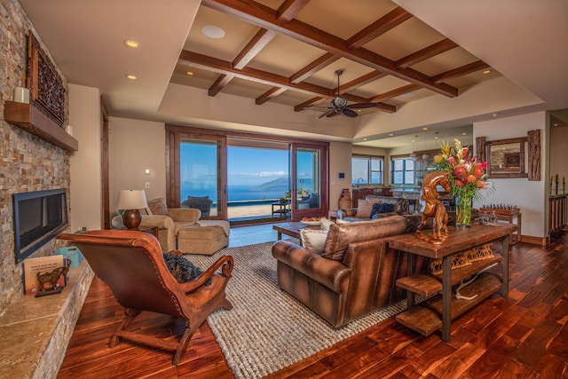 living room with a water view, a stone fireplace, coffered ceiling, and dark hardwood / wood-style flooring