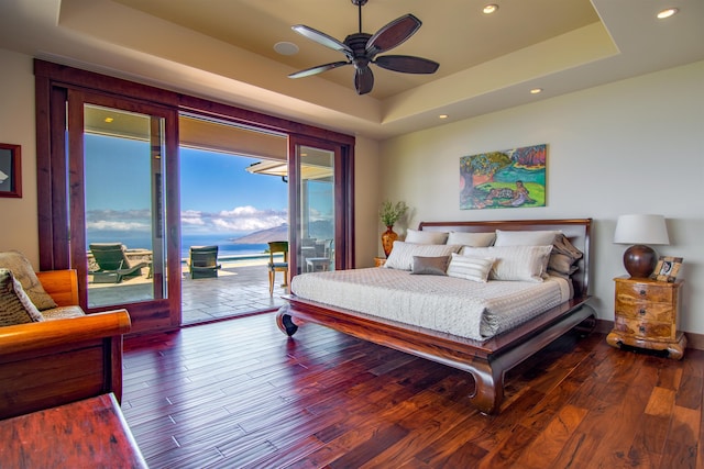 bedroom featuring access to exterior, wood-type flooring, and a raised ceiling