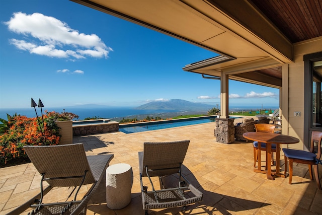 view of patio / terrace with a swimming pool with hot tub and a water and mountain view