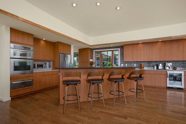 kitchen featuring wine cooler, appliances with stainless steel finishes, tasteful backsplash, and dark hardwood / wood-style floors