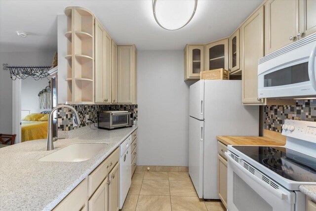 kitchen with sink, white appliances, light tile patterned flooring, and backsplash