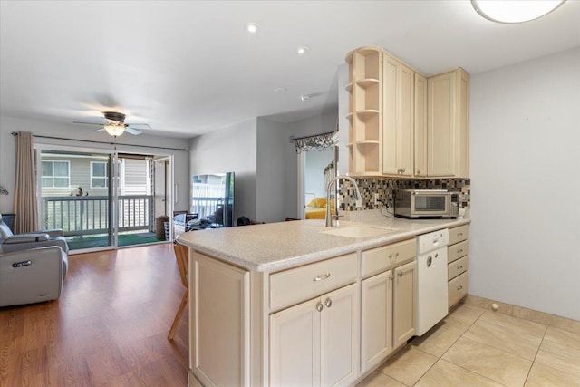 kitchen with sink, backsplash, white dishwasher, kitchen peninsula, and cream cabinets