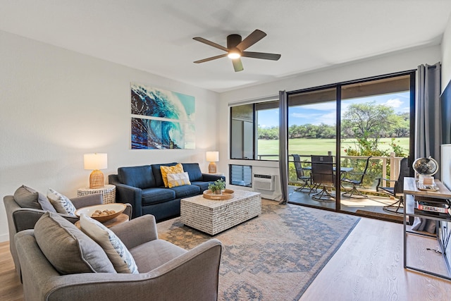 living room with a wall mounted AC, wood-type flooring, and ceiling fan