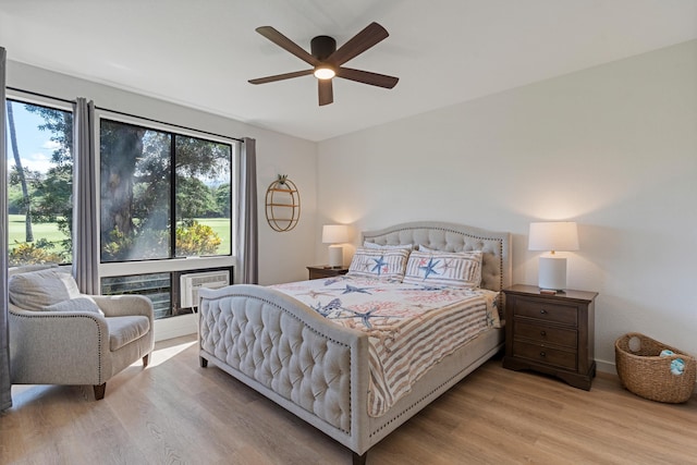 bedroom featuring ceiling fan, a fireplace, and light hardwood / wood-style flooring