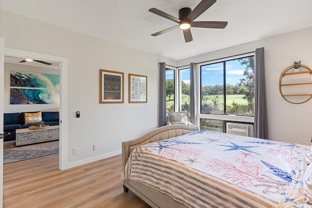 bedroom with ceiling fan, a wall unit AC, and wood-type flooring