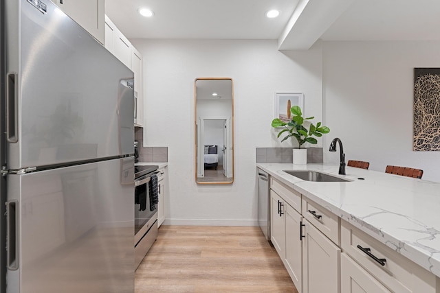 kitchen with light hardwood / wood-style flooring, sink, appliances with stainless steel finishes, and white cabinetry