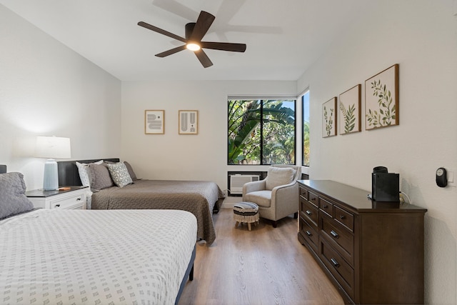 bedroom featuring a wall mounted AC, ceiling fan, and hardwood / wood-style flooring