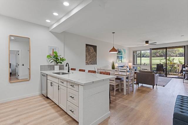 kitchen with a wealth of natural light, ceiling fan, sink, and light stone counters