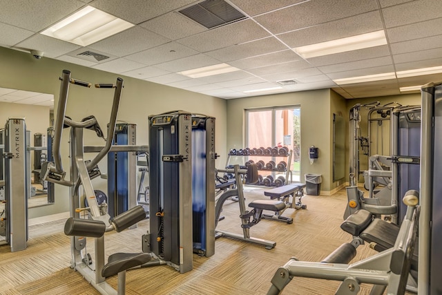 gym with carpet, visible vents, a paneled ceiling, and baseboards