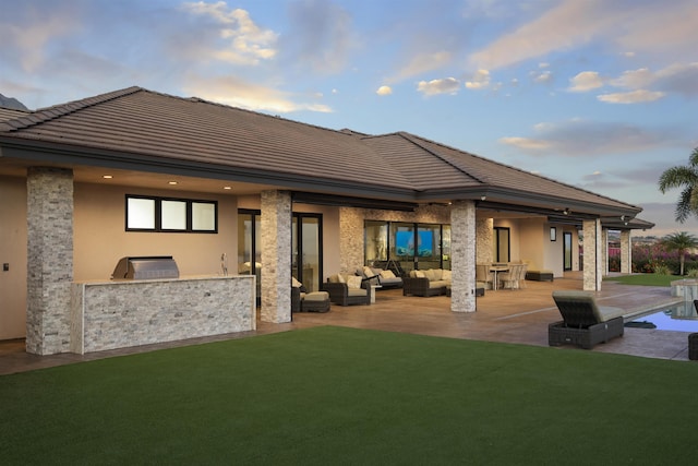 back house at dusk featuring an outdoor hangout area, a patio area, area for grilling, and a lawn