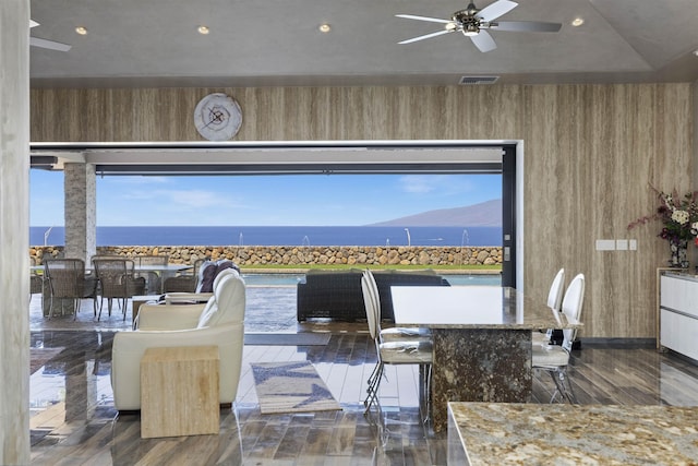 interior space featuring a water view, a healthy amount of sunlight, ceiling fan, and wooden walls