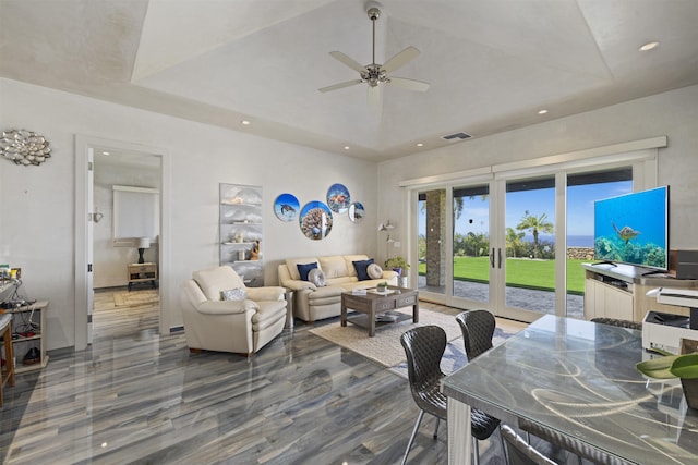 living room featuring ceiling fan, a raised ceiling, and french doors