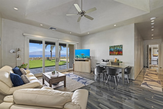 living room with ceiling fan, dark wood-type flooring, a raised ceiling, and french doors