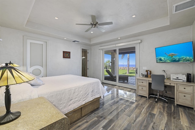 bedroom featuring dark hardwood / wood-style floors, access to exterior, a raised ceiling, and ceiling fan